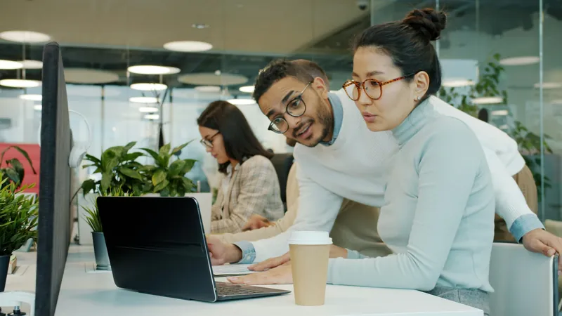 Two colleagues working through a problem together on a laptop