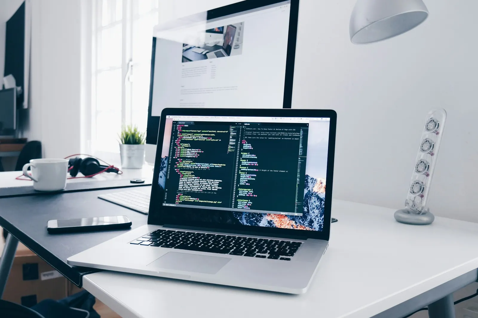 MacBook showing code on a bright, tidy desk